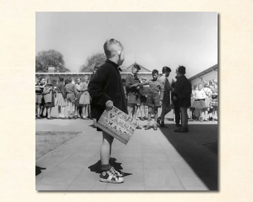 jongentje_met_leesplank_op_schoolplein